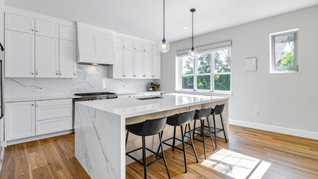 A high-end kitchen remodel by Best Pinellas Contractor, featuring timeless white Shaker cabinets, a quartz waterfall island, and hardwood floors.