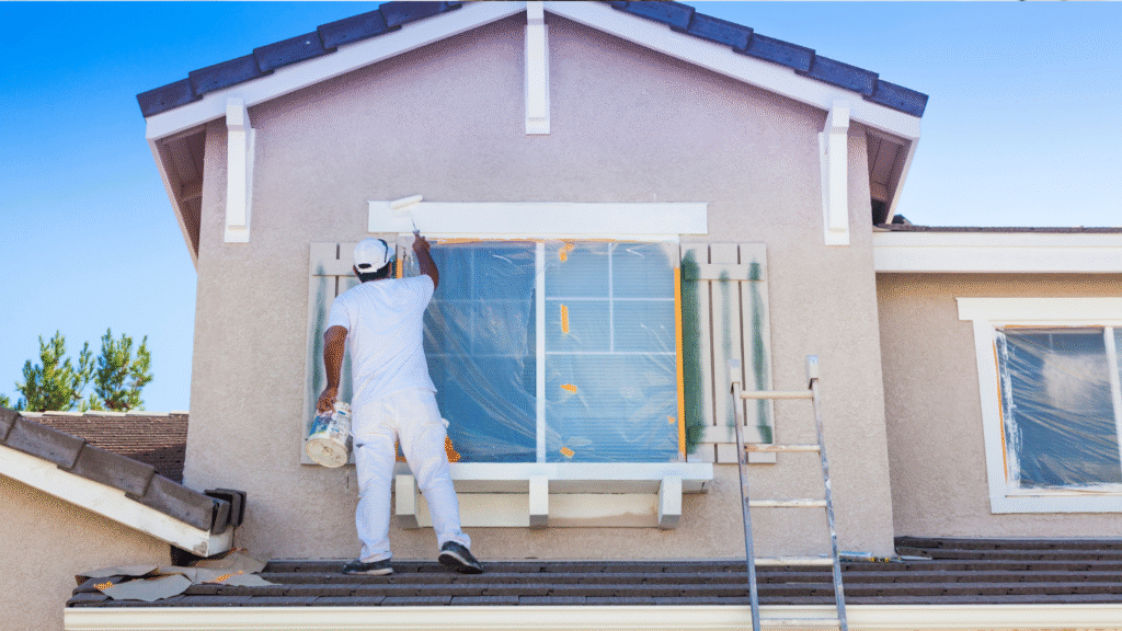 Professional contractor repairing and repainting a stucco home exterior, sealing cracks and protecting the structure from Florida sun, salt, and humidity.